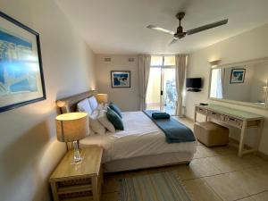a bedroom with a bed and a desk in it at Kyalanga Beachfront Apartment in Durban