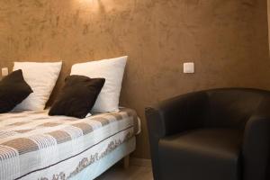 a bed with two pillows and a chair in a room at Hotel Alizéa in Avignon