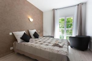 una camera con un letto con una coperta a scacchi e una finestra di Hotel Alizéa ad Avignone