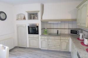 a kitchen with white cabinets and a clock on the wall at La belle endormie - appartement B in Fénétrange