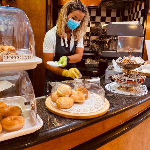 una mujer usando una máscara en una cocina preparando comida en Hotel Daniel en Basiano