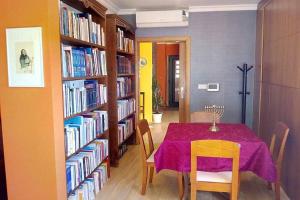a dining room with a table and shelves of books at Casa da Oliveira in Milhão