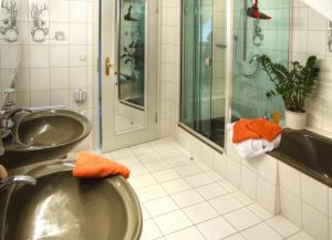 ein Badezimmer mit einem Waschbecken und einer Dusche mit orangefarbenen Handtüchern in der Unterkunft Aparthotel Jägerhaus in Willingen + 31 Fotos