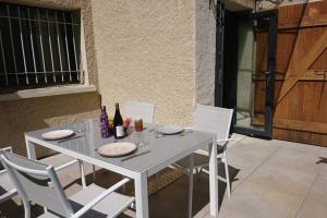 una mesa y sillas blancas con botellas y platos. en Gîte de charme en Ardèche : vue panoramique, plage privée en Saint-Fortunat-sur-Eyrieux