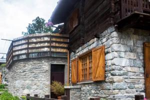 a stone building with wooden windows and a balcony at Chalet indipendente in centro a Valtournenche in Valtournenche