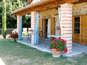 Casa de ladrillo con patio con mesa y flores en Holiday Home Belvedere - BLU101 by Interhome, en Bagni di Lucca