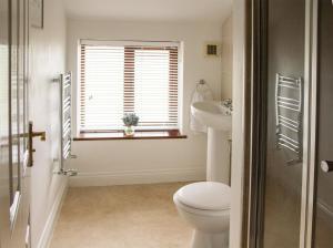 La salle de bains est pourvue de toilettes, d'un lavabo et d'une fenêtre. dans l'établissement 2 Barge Cottage, à Narborough