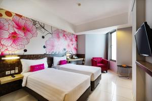 two beds in a hotel room with pink flowers on the wall at favehotel - Pantai Losari Makassar in Makassar