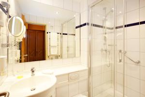 La salle de bains blanche est pourvue d'un lavabo et d'une douche. dans l'établissement Hotel Anna Amalia, à Weimar