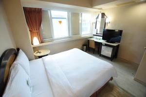 高雄市にあるKindness Hotel Weiwuyingのベッドとテレビが備わるホテルルームです。
