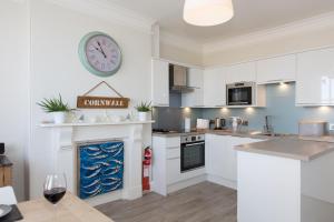 a kitchen with white cabinets and a clock on the wall at The Loft in St Ives +8 photos