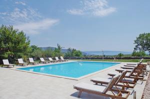 a pool with chaise lounge chairs and a bunch ofitures at Holiday apartments in house Sanja in Rakalj