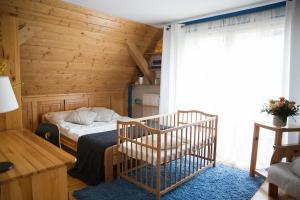 a bedroom with a crib in a room with wooden walls at Śmietanówka Agroturystyka in Krzczonów