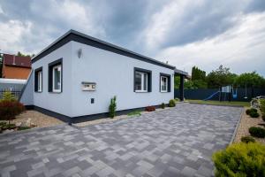 a white house with a driveway at Garden Lux Apartman in Hajdúszoboszló