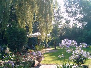 a garden with flowers and an umbrella and trees at B&B Jossefin Tuinen in Lanaken