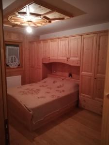 - une chambre avec un lit et des placards en bois dans l'établissement App. Frassino, à Sappada