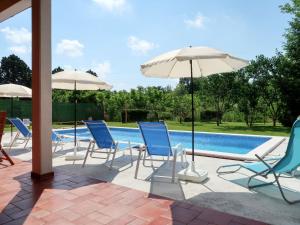 a group of chairs and umbrellas next to a pool at Apartment Ornela - LBN321 by Interhome in Nedeščina