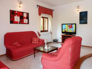 a living room with two red chairs and a tv at Apartment Ornela - LBN321 by Interhome in Nedeščina