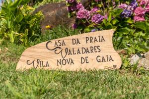 ein Schild im Gras vor einigen Blumen in der Unterkunft Casa da Praia em Valadares in Vila Nova de Gaia