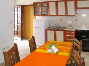 a kitchen with an orange table and a white refrigerator at Apartment Teo - LBN153 by Interhome in Labin