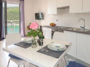 a white kitchen with a table with plates and a vase of flowers at Apartment Boris - RAC160 by Interhome in Raša
