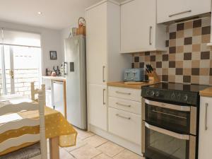 a kitchen with white cabinets and a stove top oven at Spring Cottage in Duns