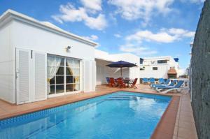 a swimming pool in front of a house at Villa Rosa in Costa Teguise