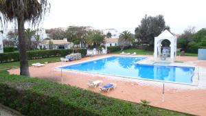 a large swimming pool with two chairs and a gazebo at Quinta Velha Village - Apart. T1 in Cabanas de Tavira