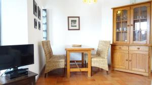 a living room with a table and chairs and a tv at Quinta Velha Village - Apart. T1 in Cabanas de Tavira