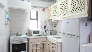 a small kitchen with a white refrigerator and a microwave at Quinta Velha Village - Apart. T1 in Cabanas de Tavira