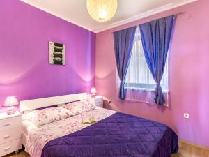 a purple bedroom with a bed and a window at Apartment Magdalena - MOD118 by Interhome in Plomin
