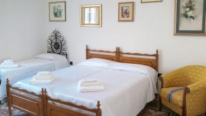 1 dormitorio con 2 camas y 1 silla en Welcomely - Casa Vacanze Zarinu, en Orgosolo