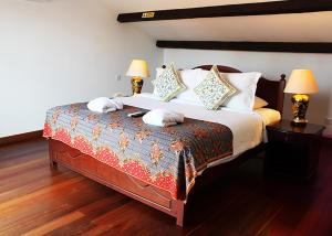 a bedroom with a large bed with two lamps at Heeren Straits Hotel in Malacca