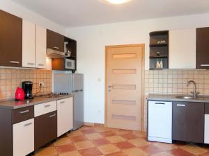 une cuisine avec des placards marron et blanc et une porte dans l'établissement Apartment Urdih - KRK316 by Interhome, à Malinska