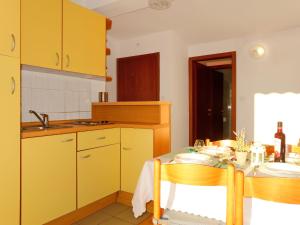 una cucina con armadi gialli, tavolo e sedie di Apartment Barbara - PUT121 by Interhome a Punat