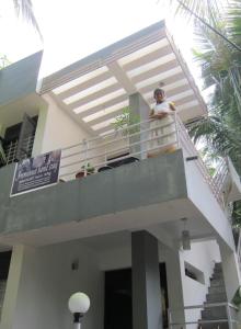 un hombre parado en el balcón de una casa en Immanuel Home Stay, en Kochi