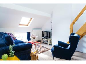 ein Wohnzimmer mit einem blauen Sofa und einem TV in der Unterkunft B&B Place Jourdan in Brüssel