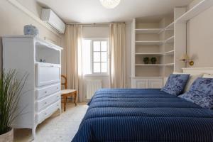 a white bedroom with a blue bed and shelves at BLUE Atlantic Family Home by Cadiz4Rentals in Cádiz