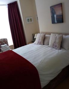 a bedroom with a large white bed with a red curtain at Cadame in Whitby