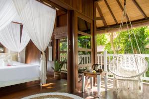 a bedroom with a bed and a table and chairs at Rasasvada cottages in Uluwatu