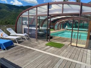 a house with a swimming pool and a wooden deck at Hôtel Restaurant Le Chalet d'Auron et Spa Inclus in Auron