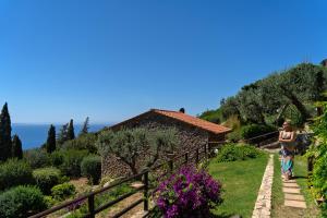 a woman walking down a path in a garden at Boutique Hotel Torre Di Cala Piccola in Porto Santo Stefano