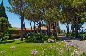 a house with trees and flowers in the yard at Boutique Hotel Torre Di Cala Piccola in Porto Santo Stefano