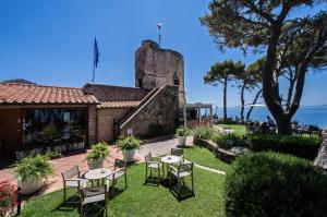 a patio with tables and chairs in front of a building at Boutique Hotel Torre Di Cala Piccola in Porto Santo Stefano
