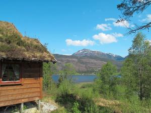 uma cabana com telhado de palha e um lago em Chalet Elisabeth - FJH664 by Interhome em Eikelandsosen