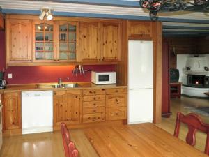 una cucina con armadi in legno, lavandino e forno a microonde di Chalet Anna - FJH661 by Interhome a Eikelandsosen