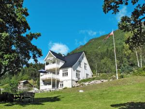 a large white house on a hill with a flag at Chalet Villa Esefjord - FJS003 by Interhome in Balestrand