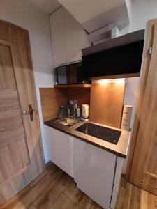 a small kitchen with a sink and a stove at Doba Rent POKOJE CENTRUM PAŁACOWA in Białystok