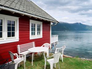 una casa rossa con un tavolo e delle sedie vicino all'acqua di Chalet Naustet by Interhome a Balestrand