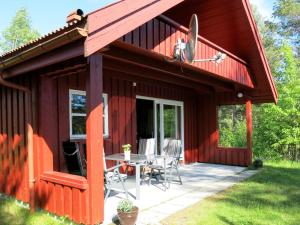 eine rote Hütte mit einem Tisch und Stühlen auf einer Terrasse in der Unterkunft Chalet Saglia - SOO020 by Interhome in Mjåvatn